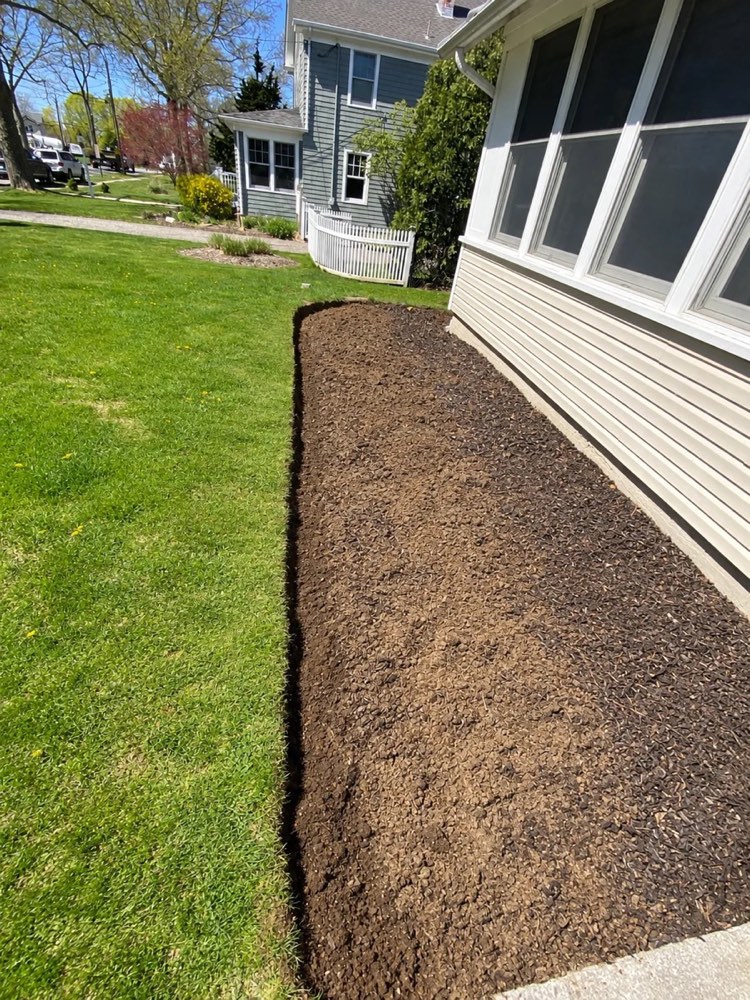Freshly edged, empty garden bed along the house before the paver border and plantings