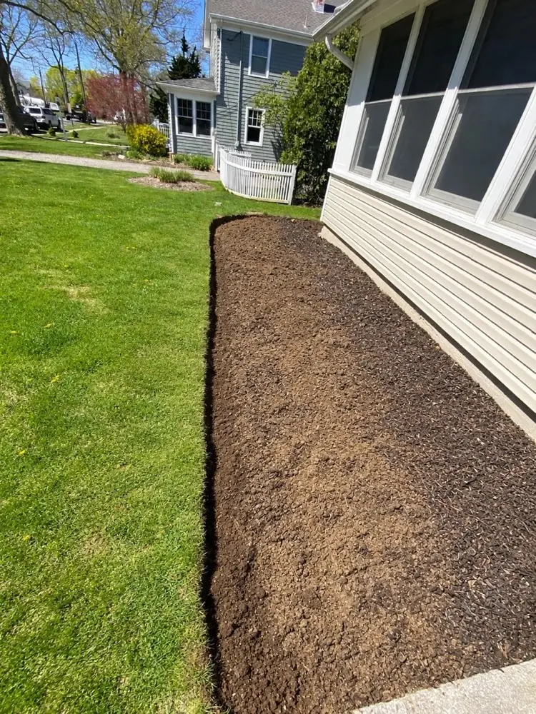Freshly edged, empty garden bed along the house before the paver border and plantings
