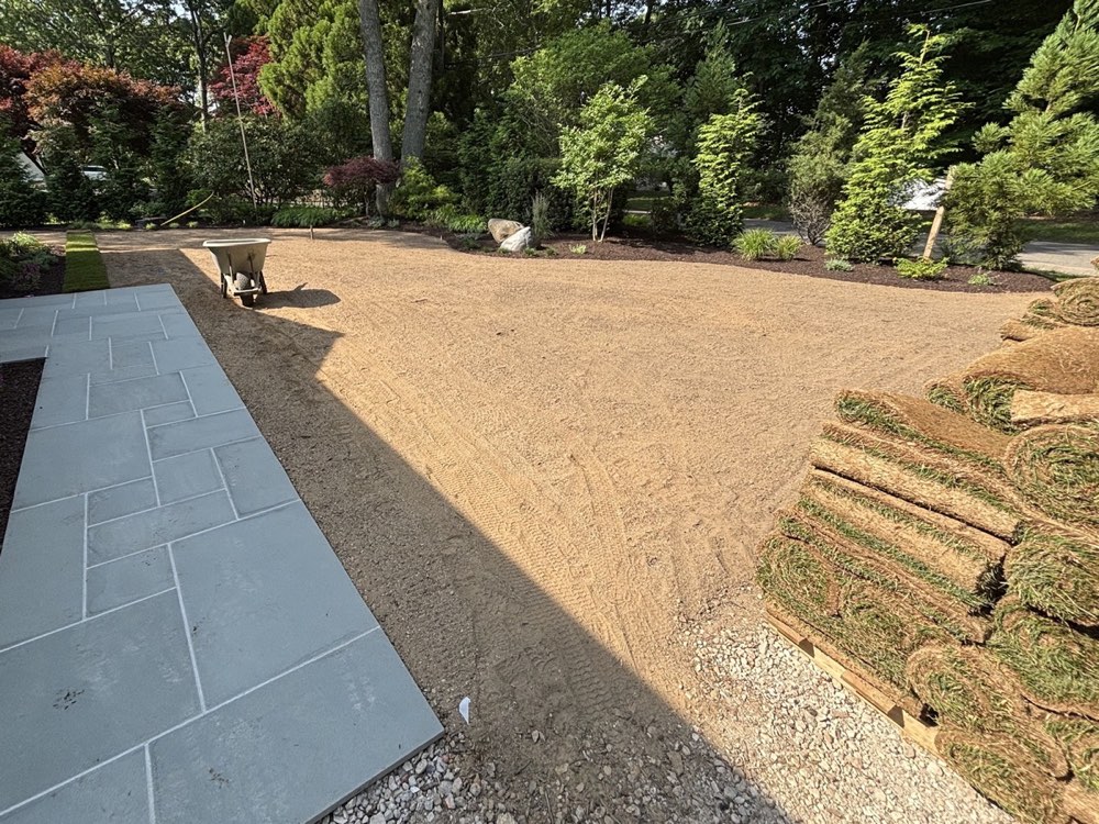 Graded bare soil ready for sod, with rolls of sod stacked on a pallet